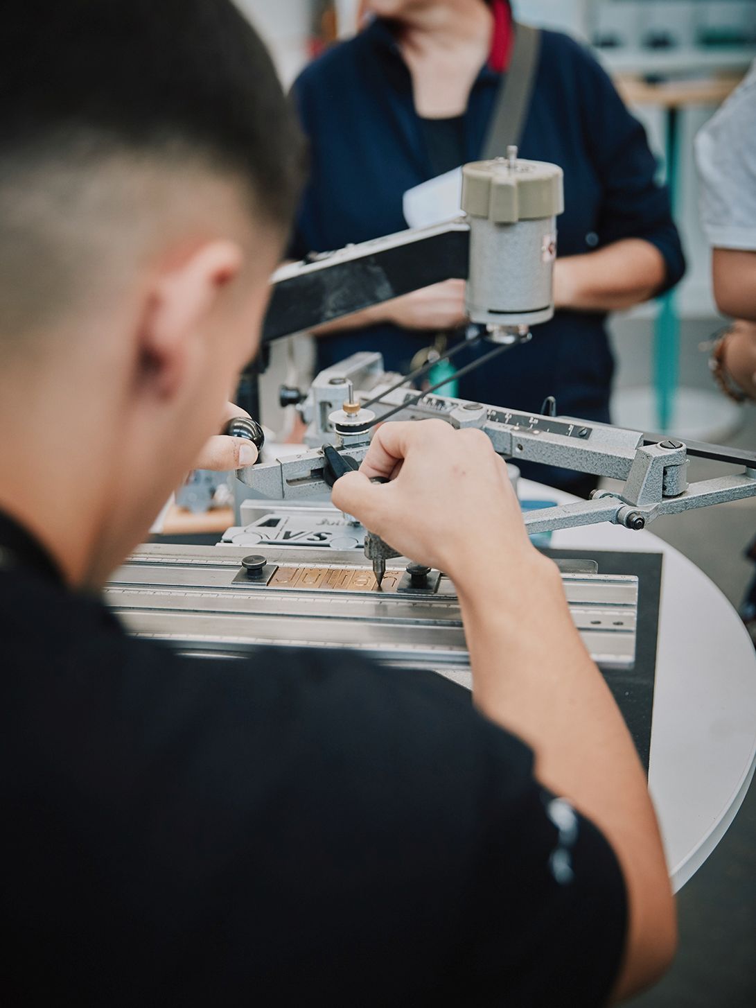 Blick über die Schulter eines VS-Handwerkers bei der Herstellung eines Namensschilds