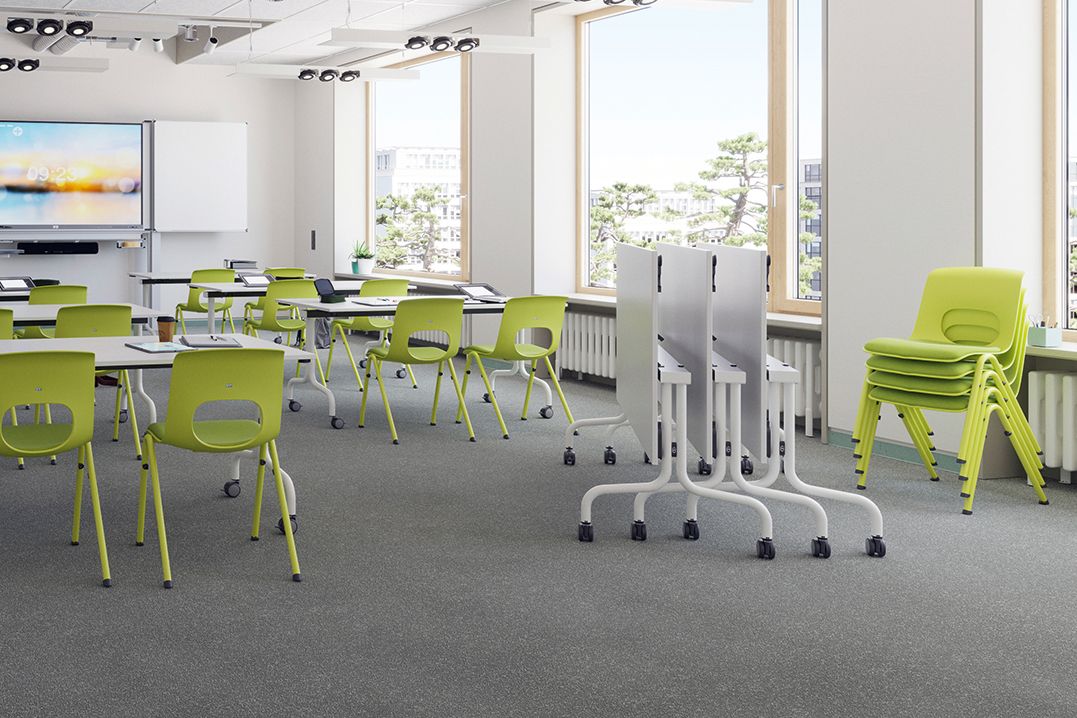 Salle de classe moderne avec les tables rabattables FlipTable, les chaises scolaires rembourrées et empilables NF-Compass et un tableau blanc interactif MediaPilon de VS