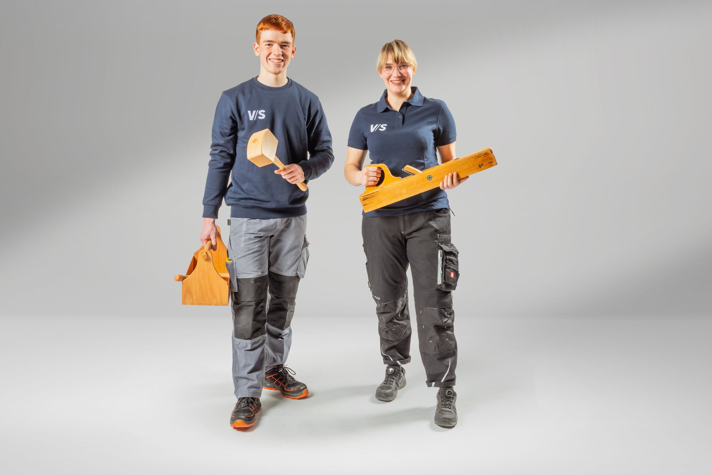 Two young people with wooden tools who are training to become wood mechanics at VS.