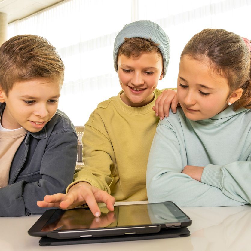 Three children learn together on one tablet