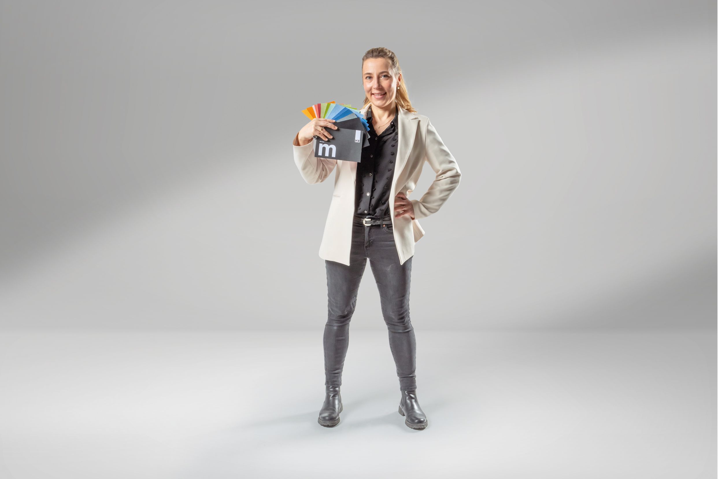 Young woman holding a material fan who is training as a technical product designer at VS.