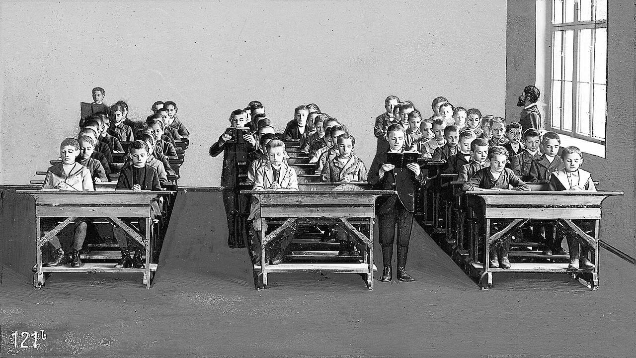 Schwarz-Weiß-Bild eines Klassenzimmers um 1900 mit Rettig-Bänken