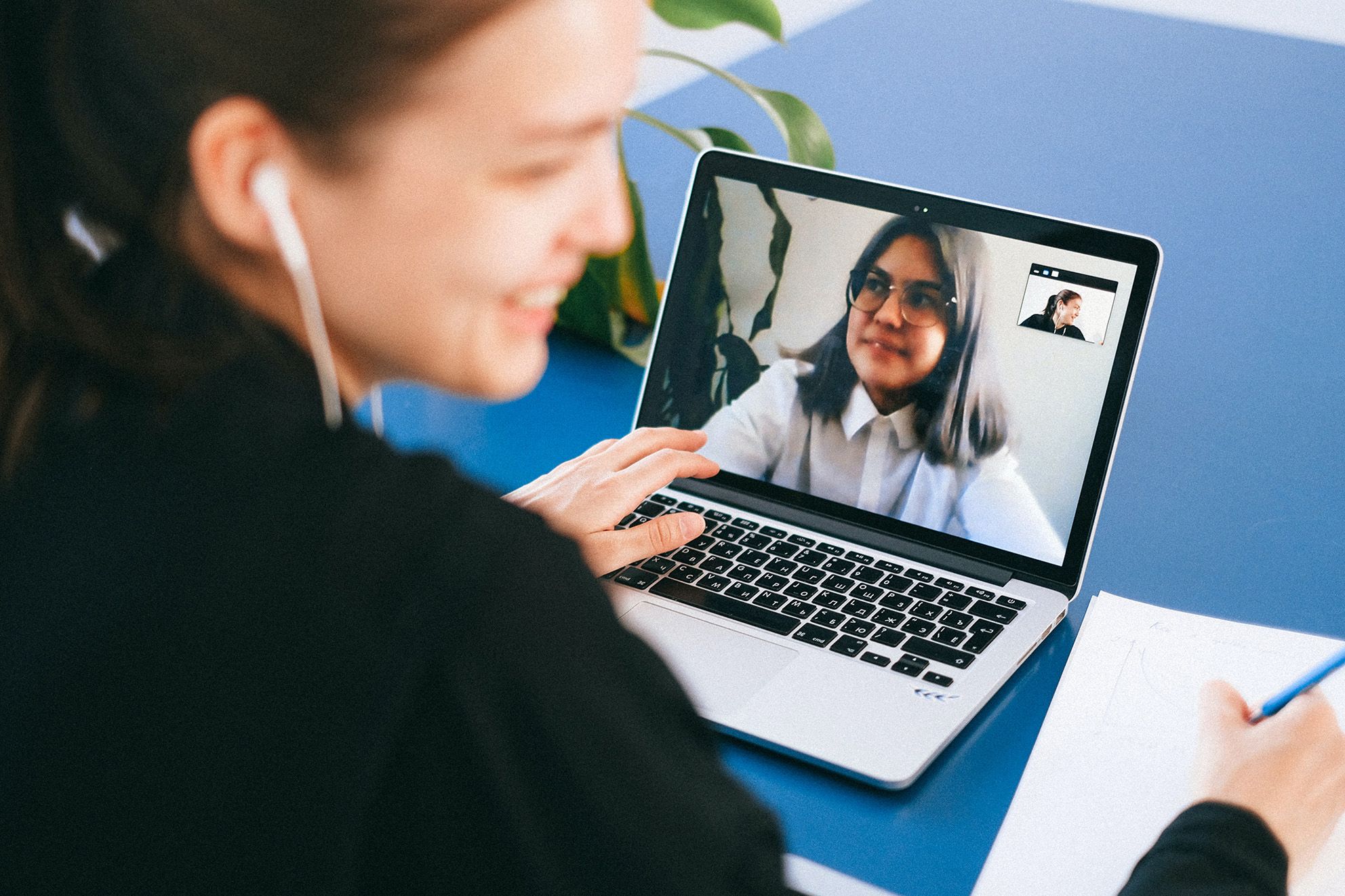 Bildausschnitt einer lächelnden Frau, die an ihrem Laptop in einem Onlinemeeting sitzt.