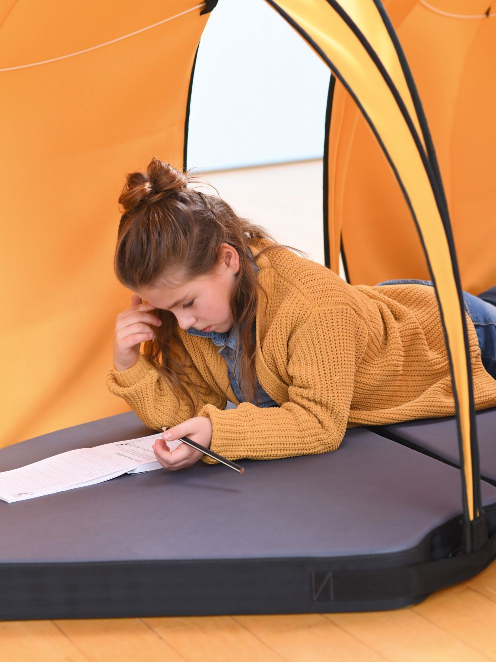 A girl is studying while lying in the tent Leaf by VS.