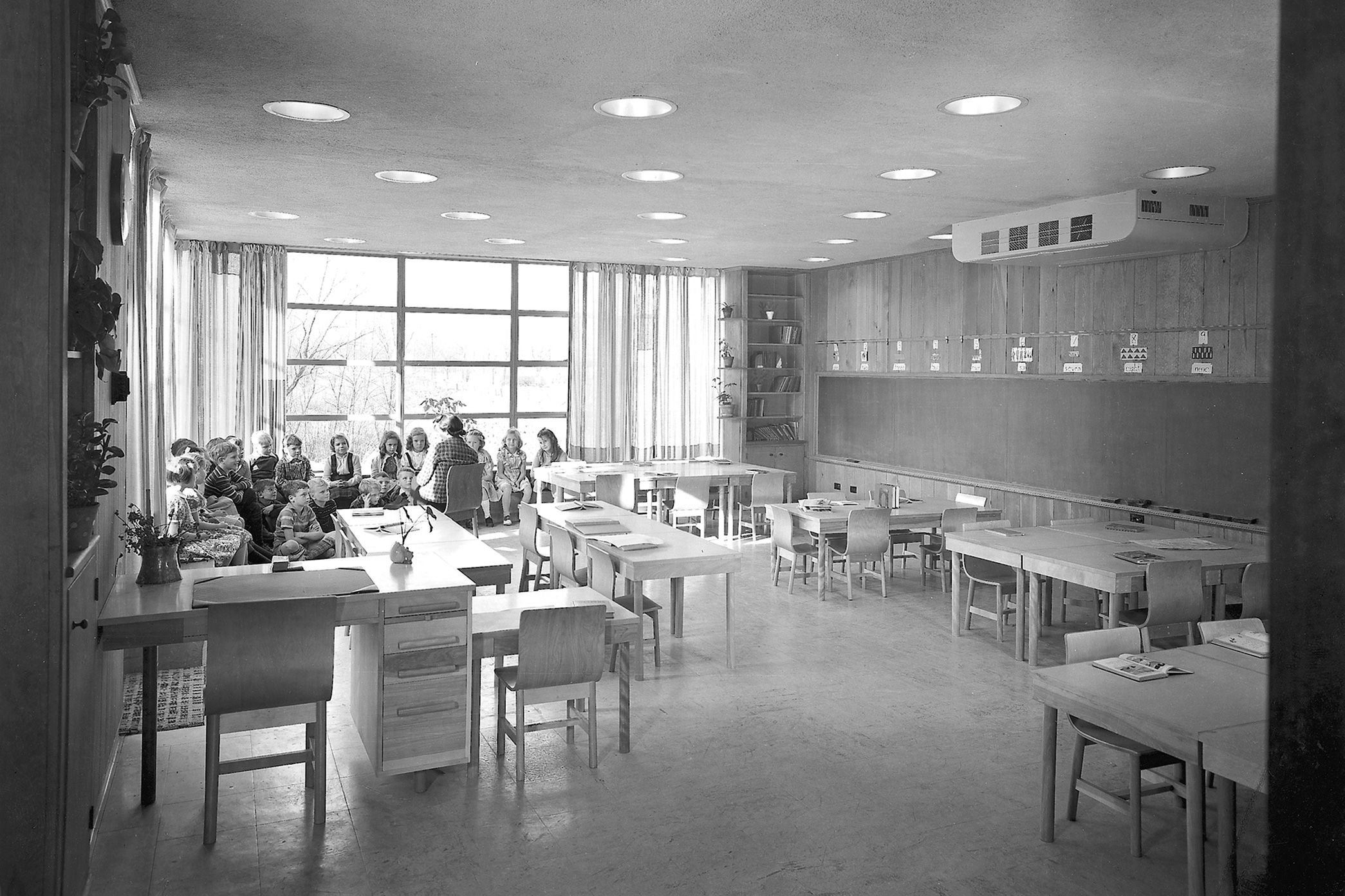 Schüler sitzen mit der Lehrerin in der Sitzecke eines Klassenzimmers in der Crow Island School in Winnetka, Illinois, USA
