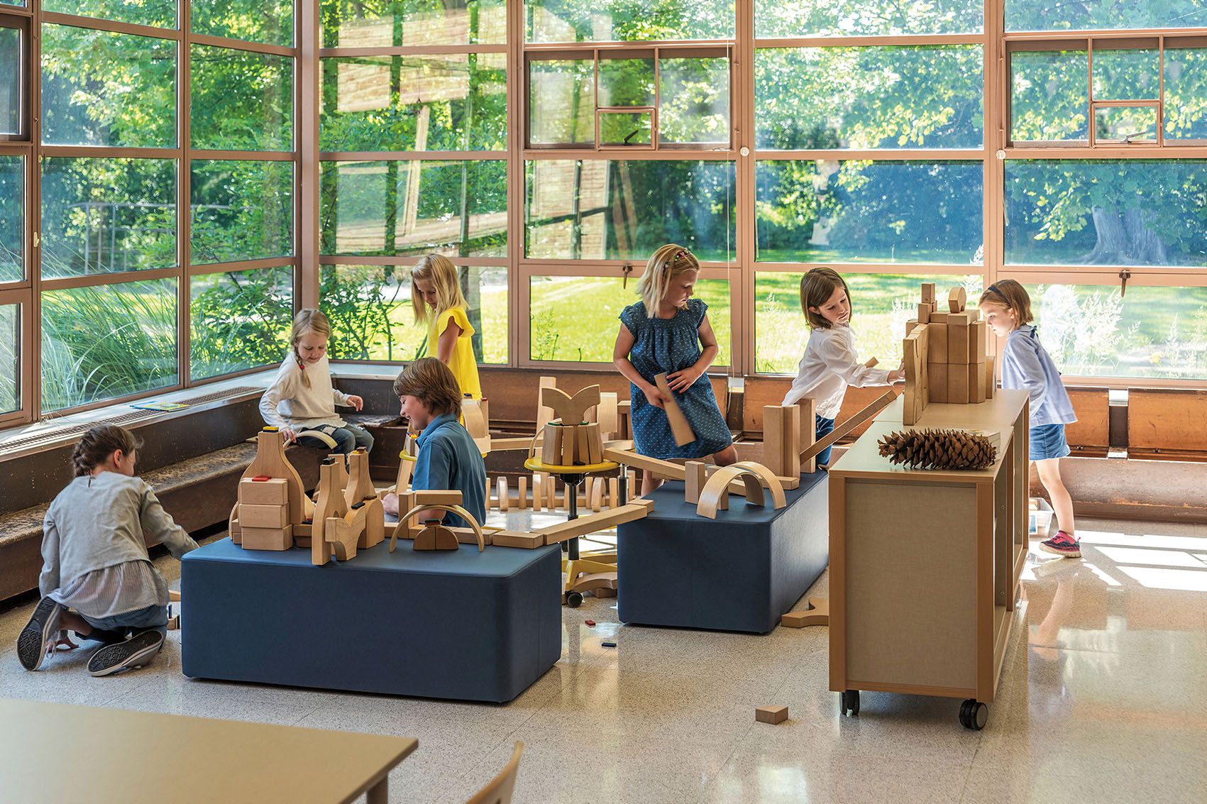 Mehrere Kinder spielen interaktiv in einem hellen Raum mit Holz-Gegenständen.