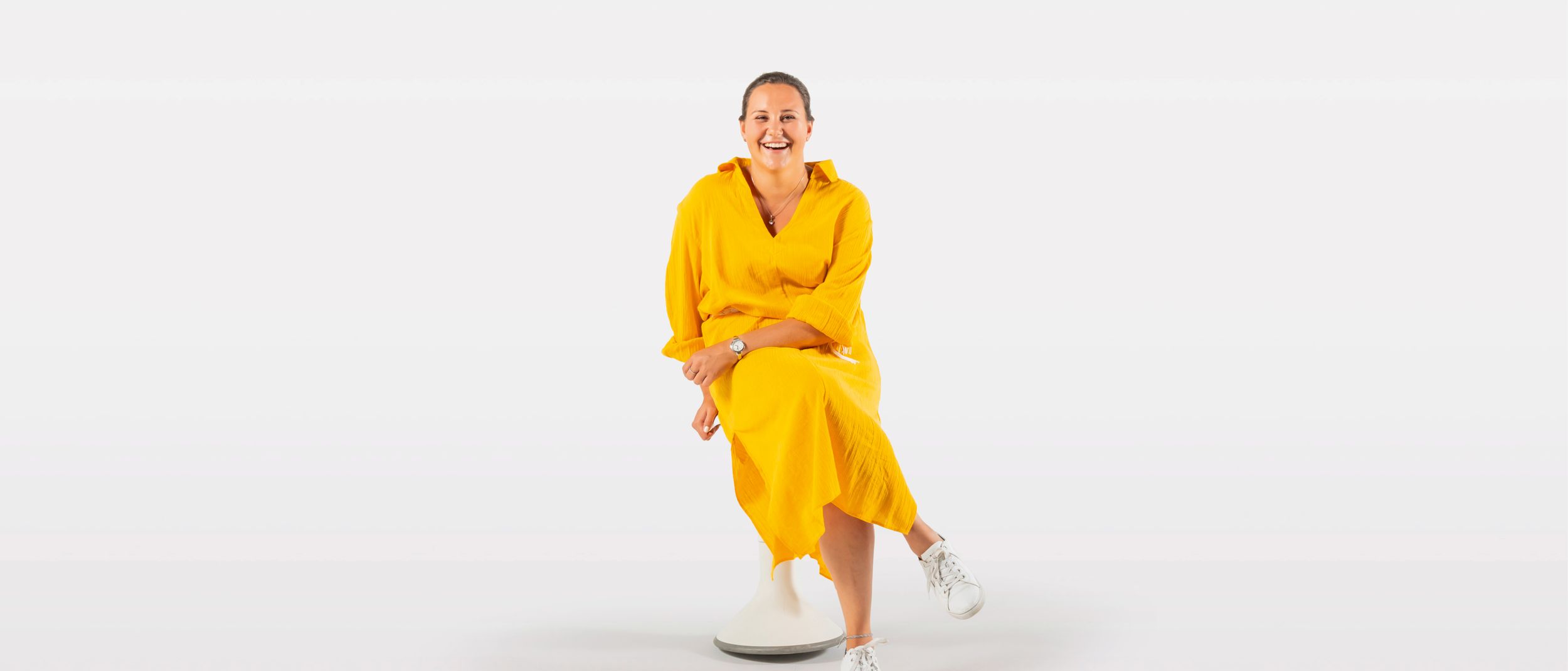 Junge Frau in gelbem Kleid sitzt auf dem ergonomischen Hocker Hokki von VS