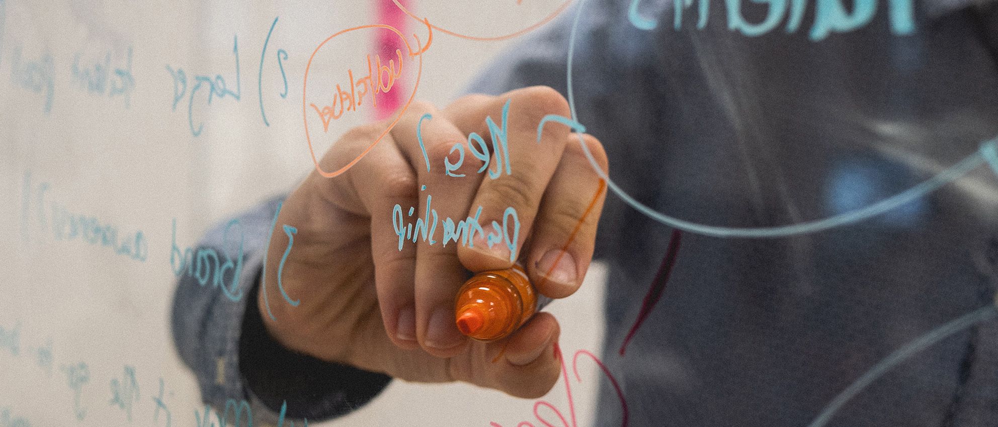 Cropped image of a person writing on a transparent board