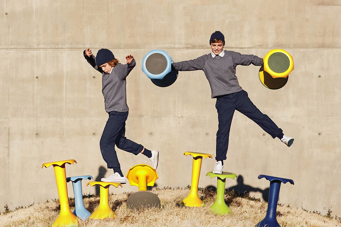 Two children balance on and play with the Hokki stools by VS outdoors