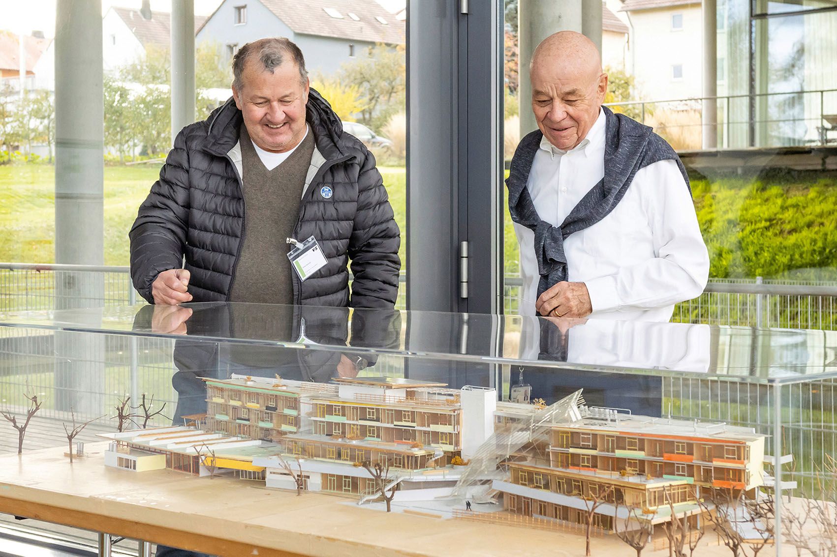 Architekt Stefan Behnisch und ehemaliger VS-Geschäftsführer Thomas Müller schauen auf das Modell eines Gebäudes
