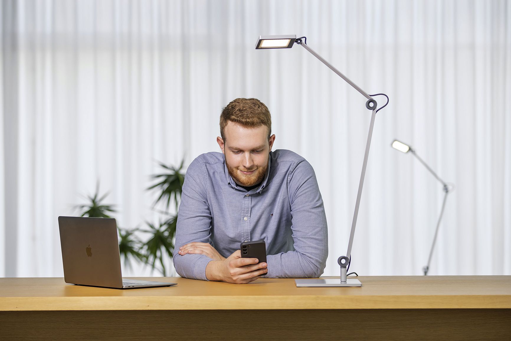 A dual student of VS sits at a table with a laptop and his mobile phone