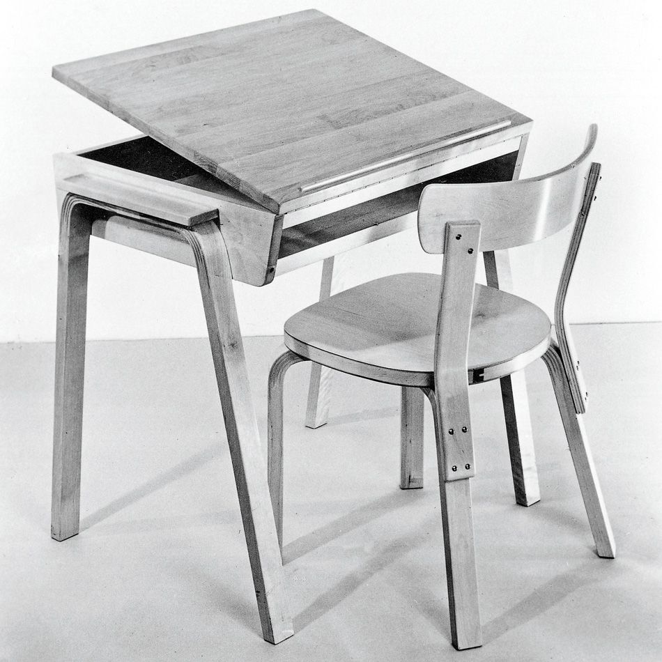 schwarz-weiß Bild von einem Holzstuhl und einem Tisch mit neigbarer Platte, entworfen vom finnischen Architekten und Möbeldesigner Alvar Aalto in den 1930er bis 1950er Jahren