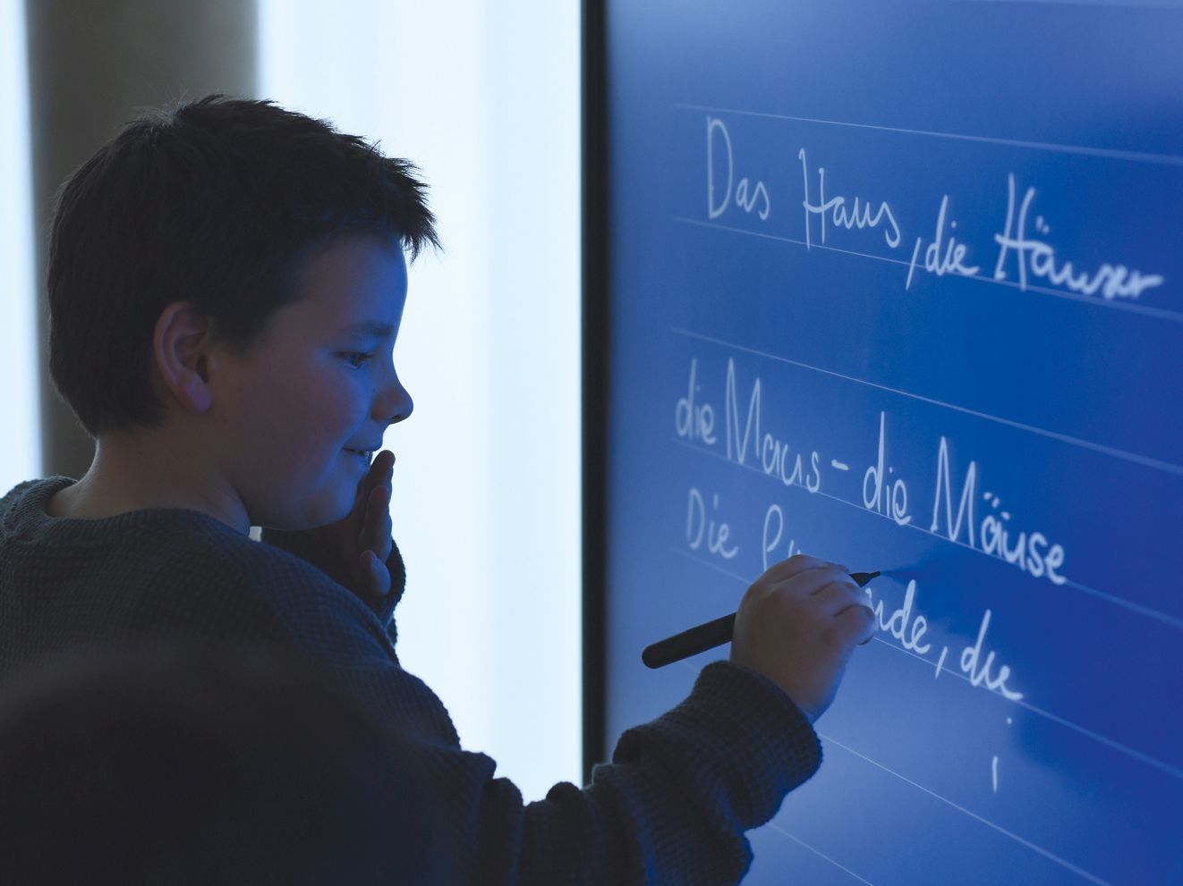 Ein Junge schreibt auf ein interaktives Whiteboard.