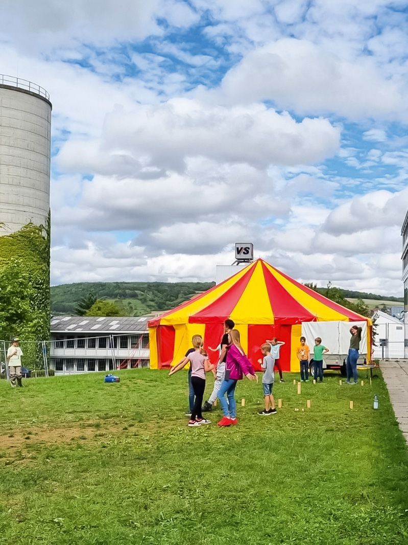 Kinder spielen vor einem Eventzelt bei der VS-Ferienbetreuung Holzwürmer