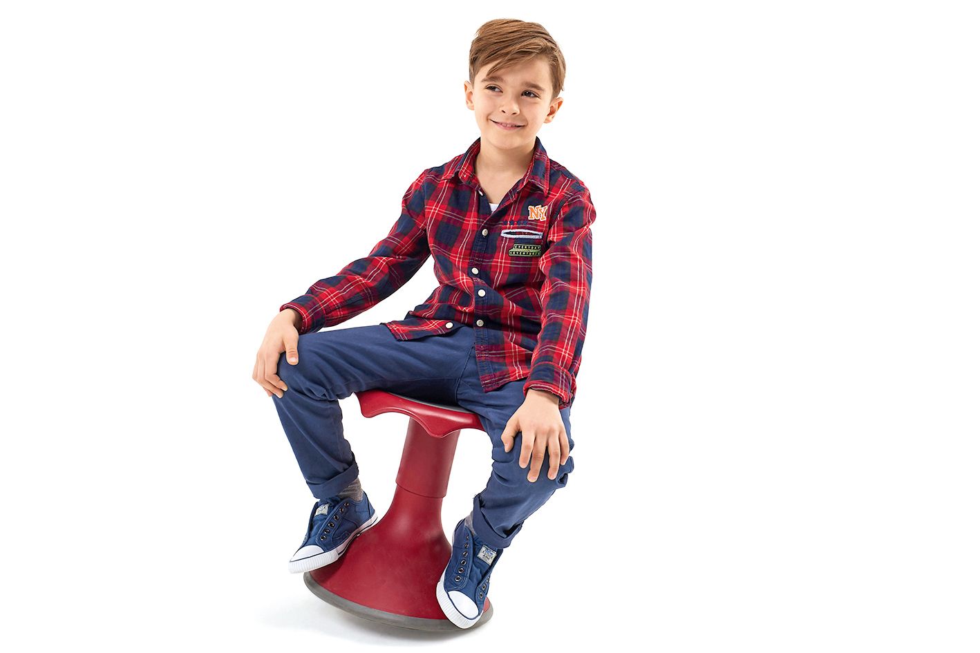 A smiling boy sits on a small, red Hokki by VS