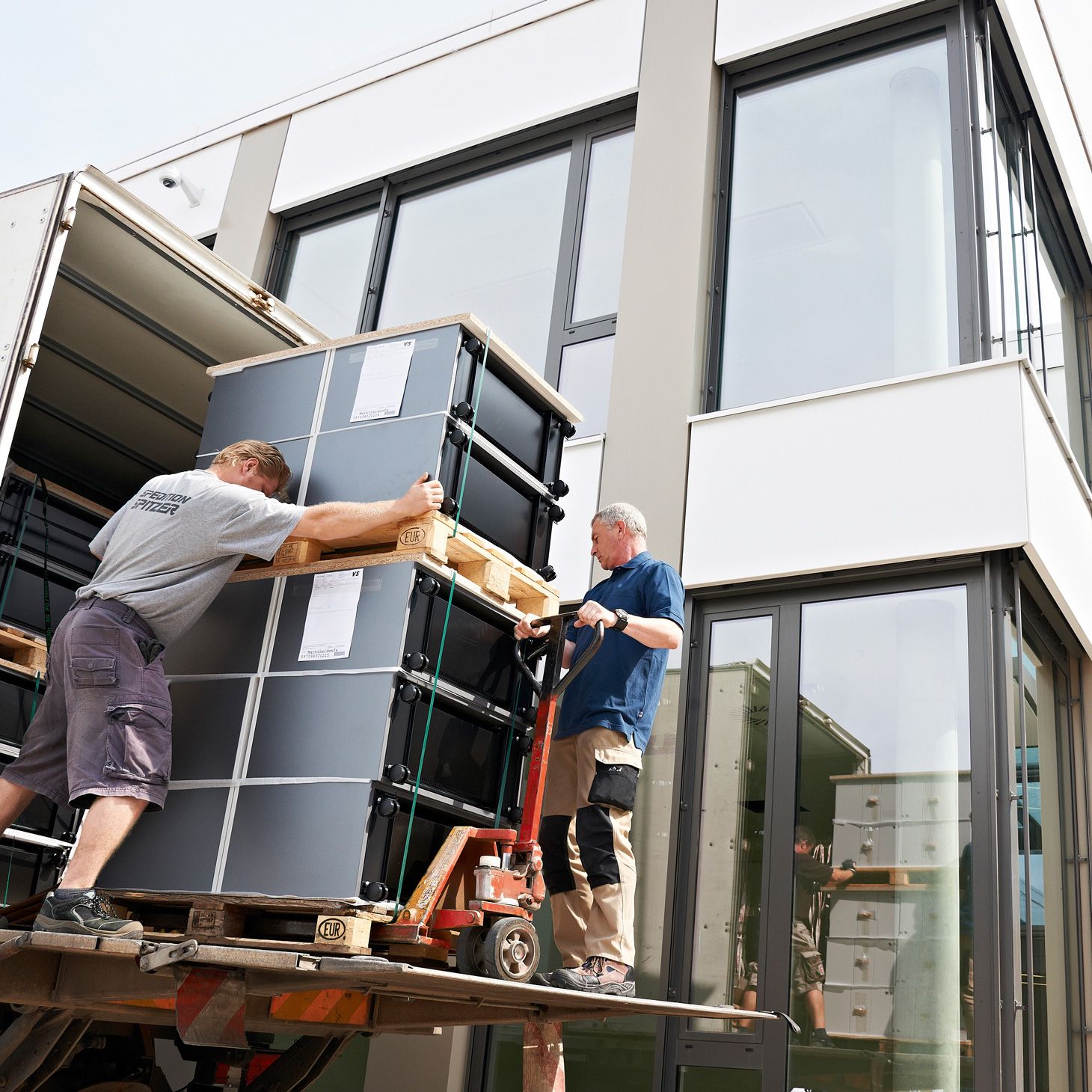 Two men load a lorry with a pallet of VS mobile cabinets.