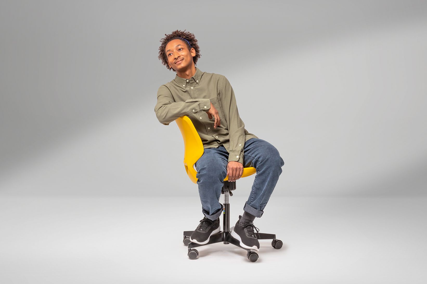 A young man sits sideways on a yellow JUMPER Air swivel chair by VS