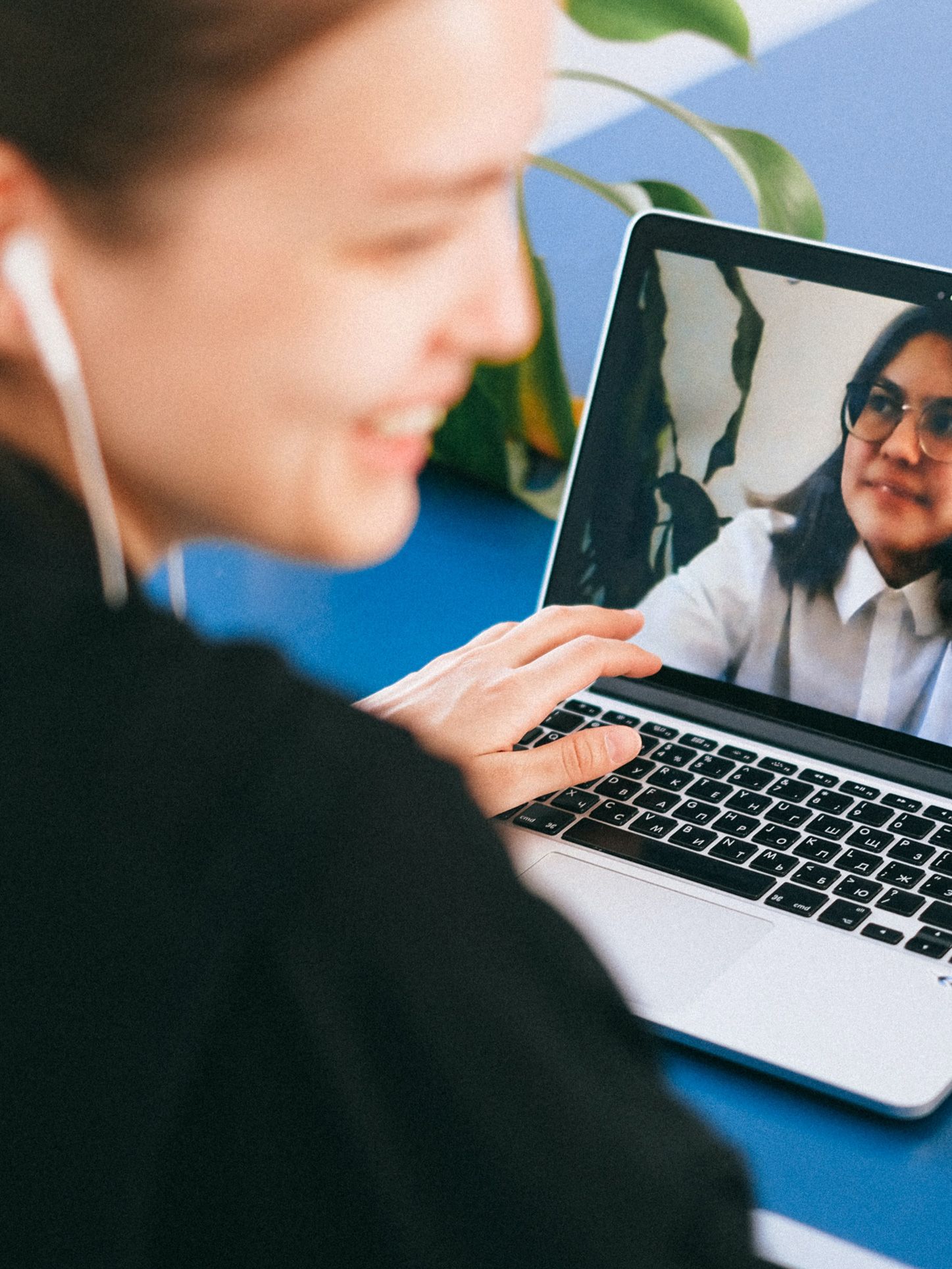Bildausschnitt einer lächelnden Frau, die an ihrem Laptop in einem Onlinemeeting sitzt.