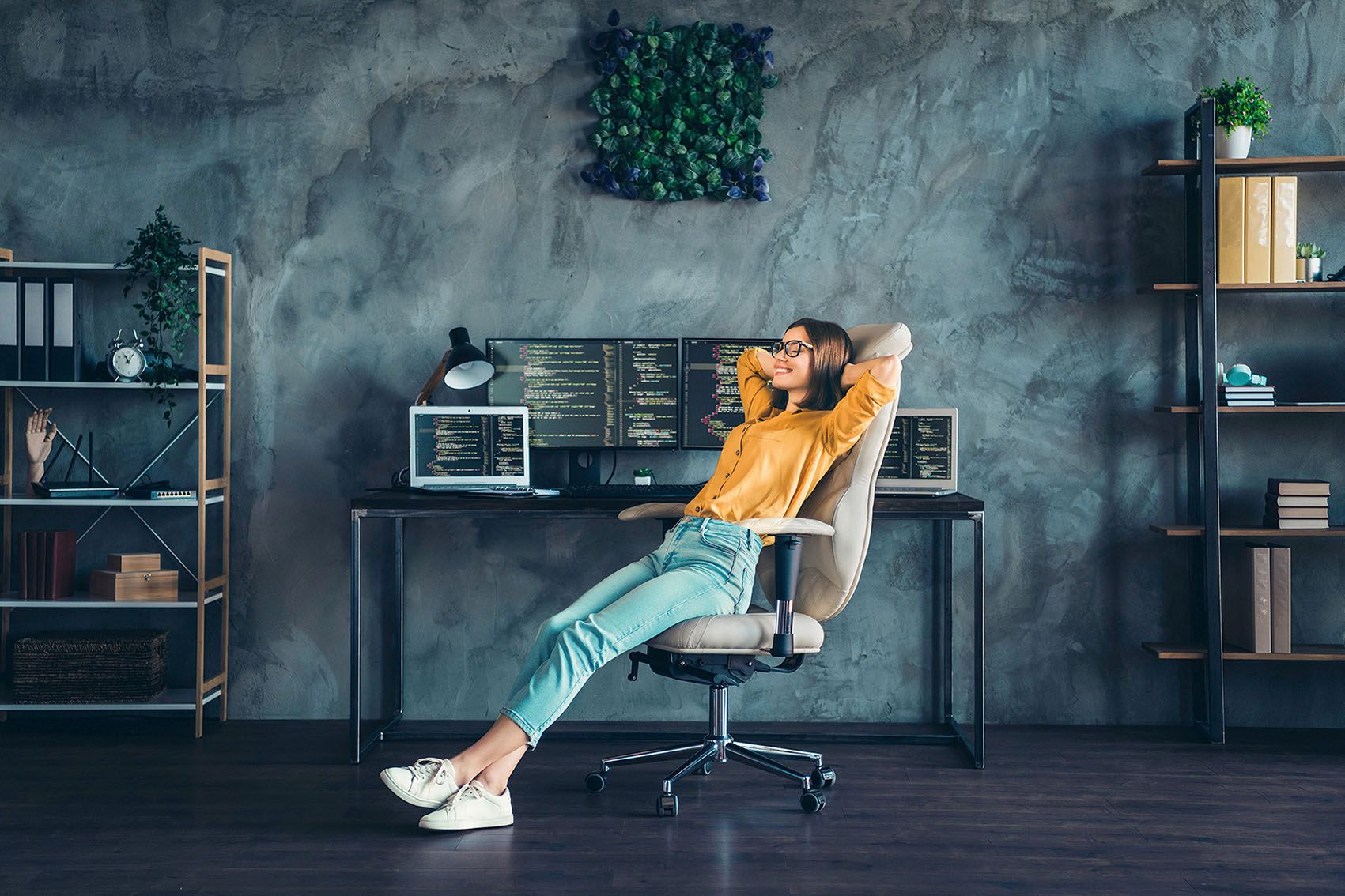 A young woman leans back and relaxes in her swivel chair in her home office