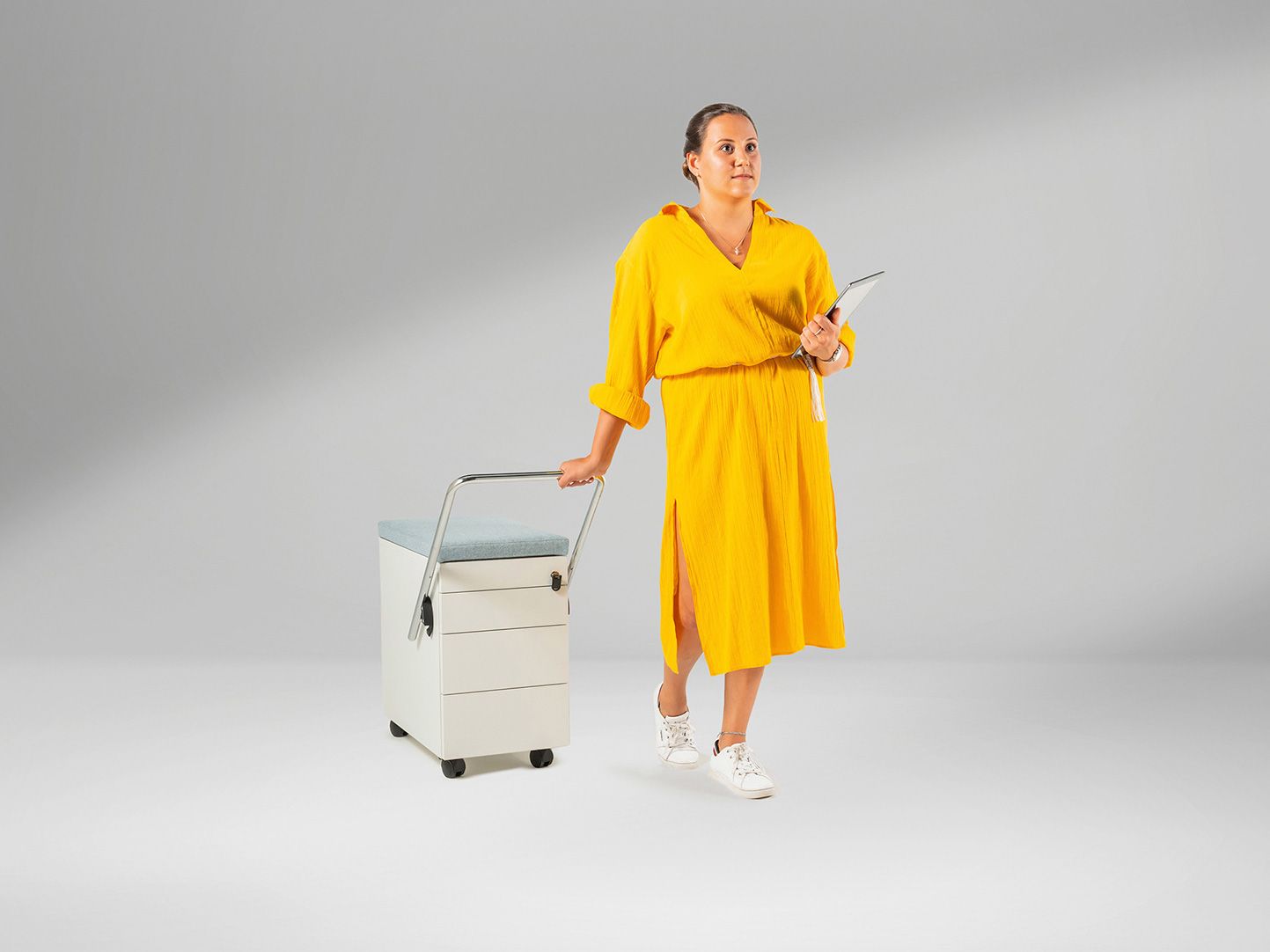 Young woman in yellow dress pulls mobile filing cabinet OfficeBox by VS behind her.