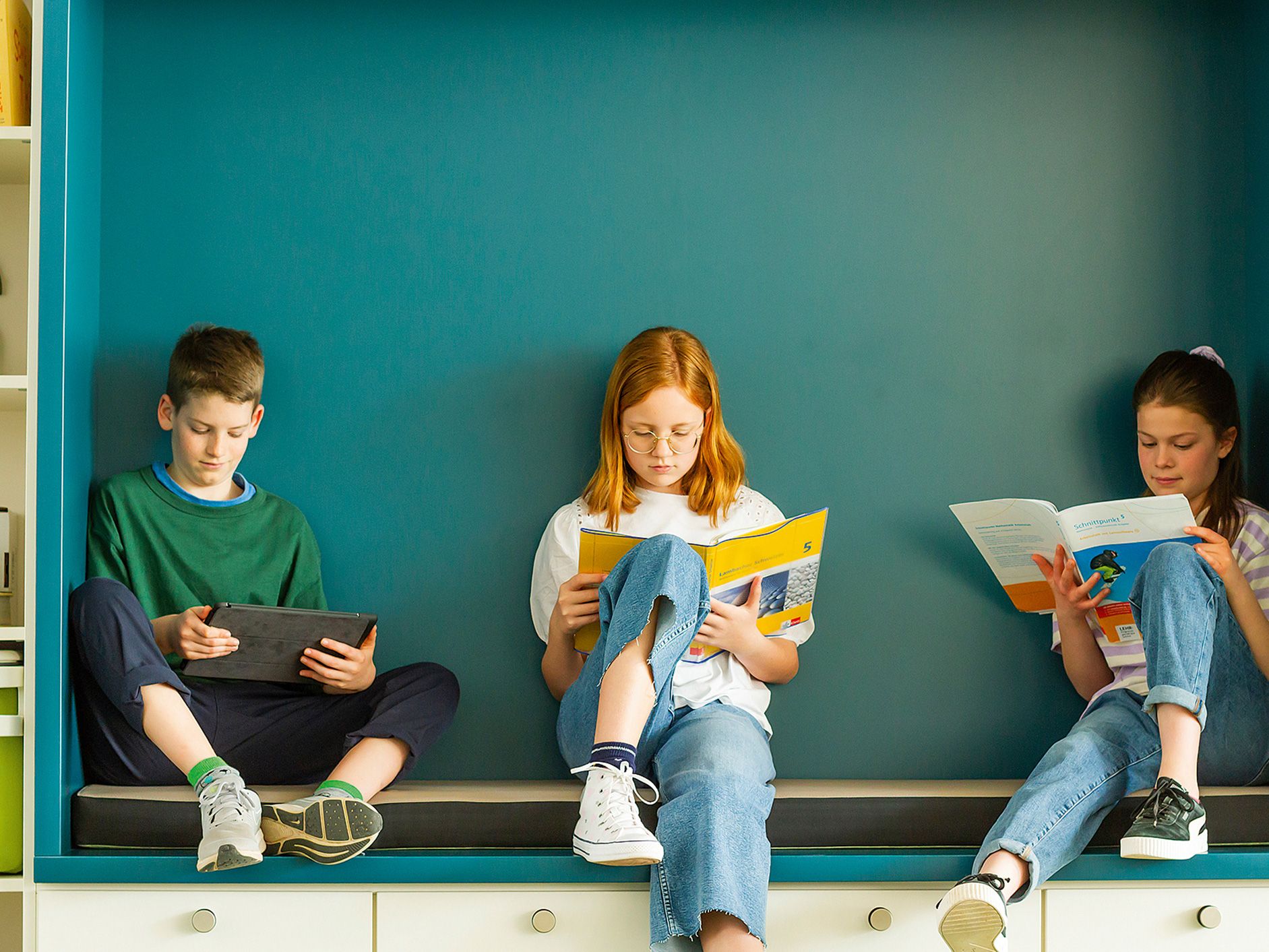 Three children sit in an alcove and read