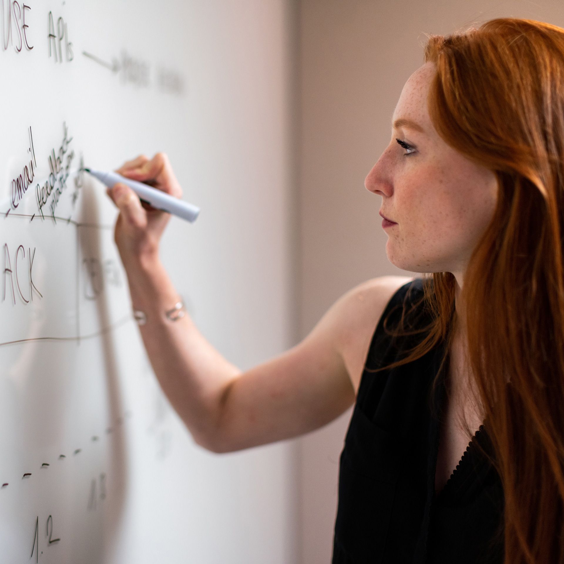 A woman writes on a whiteboard.