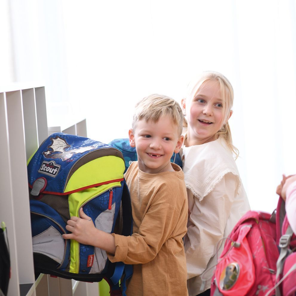 Children take their schoolbags out of a VS cupboard