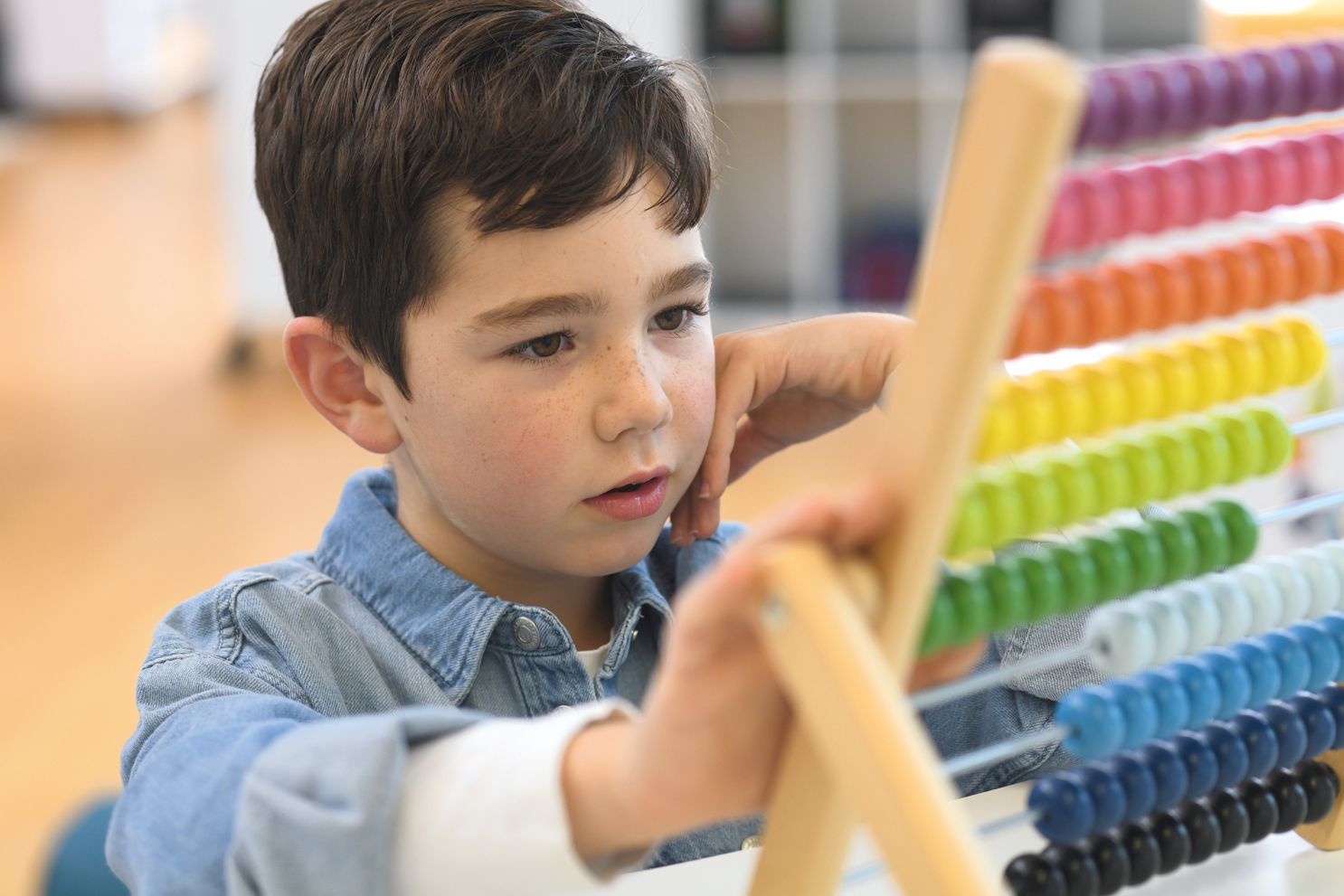 A boy learns arithmetics with an abacus on floor-level furniture from the FloorFriends series by VS.