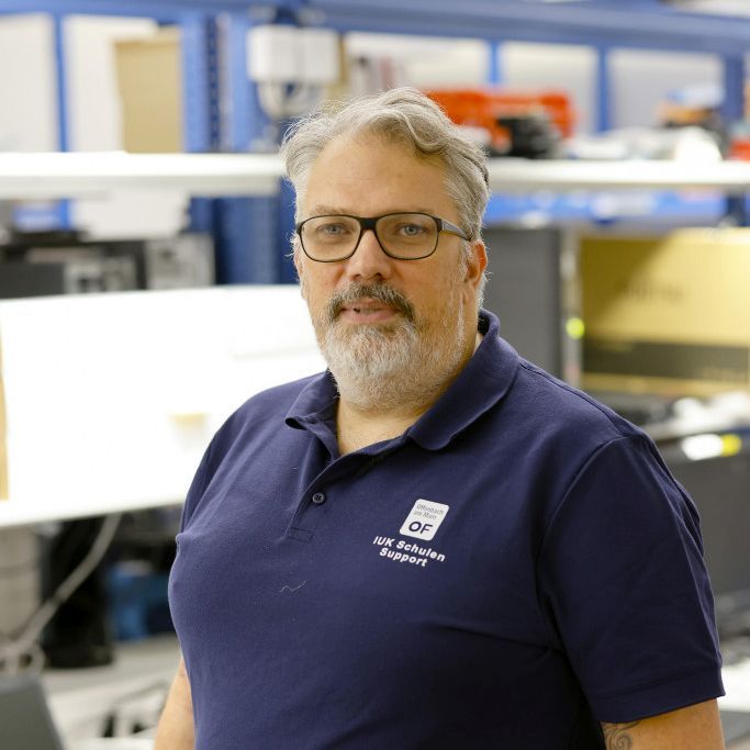 A man stands in a production facility and looks into the camera