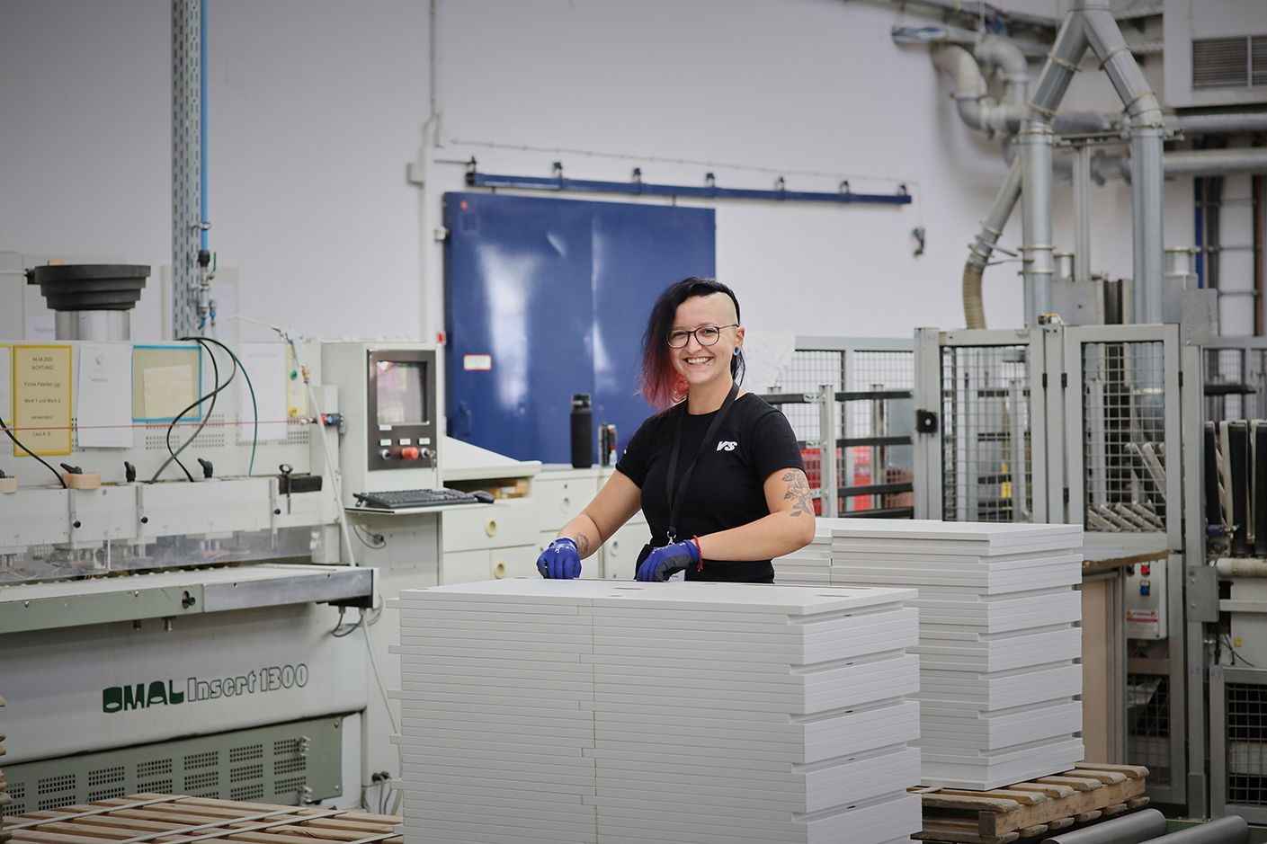 Eine Fachkraft für Lagerlogistik steht im Werk der VS und lächelt in die Kamera
