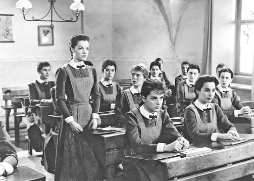 Black and white image of girls sitting on school benches