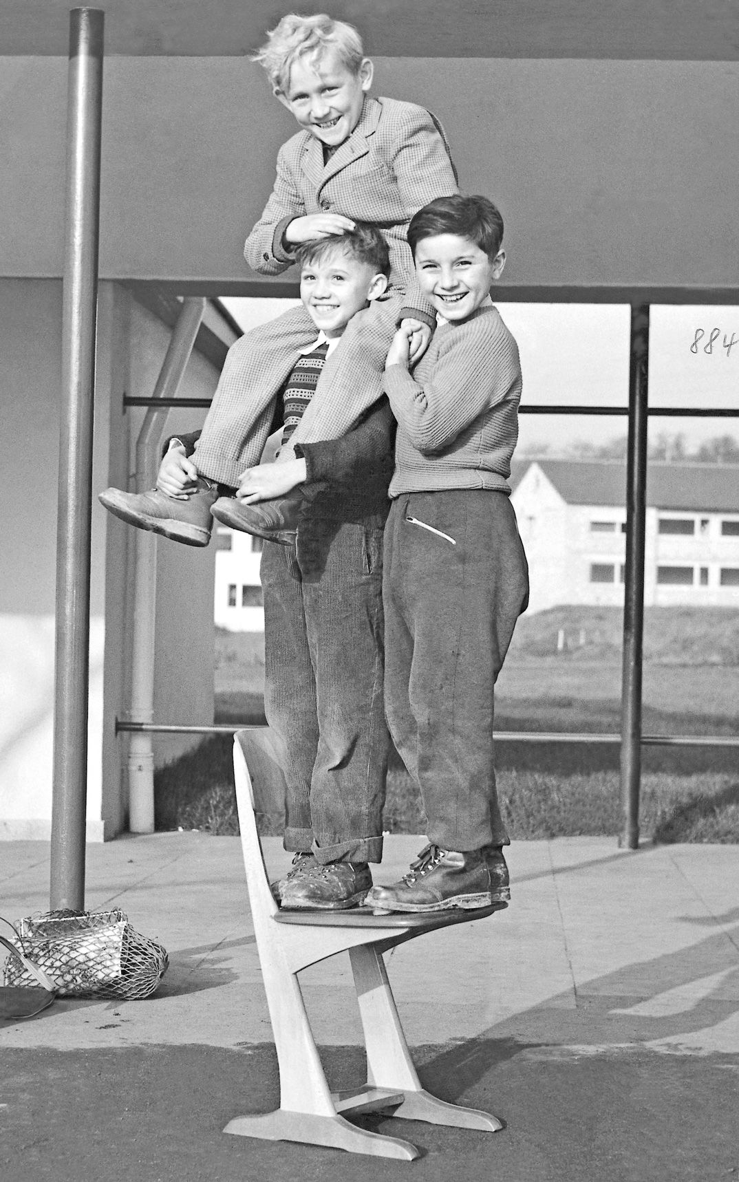 Schwarz-Weiß-Bild von 1950 von drei Kindern, die gemeinsam auf einem Holzkufenstuhl von VS stehen.