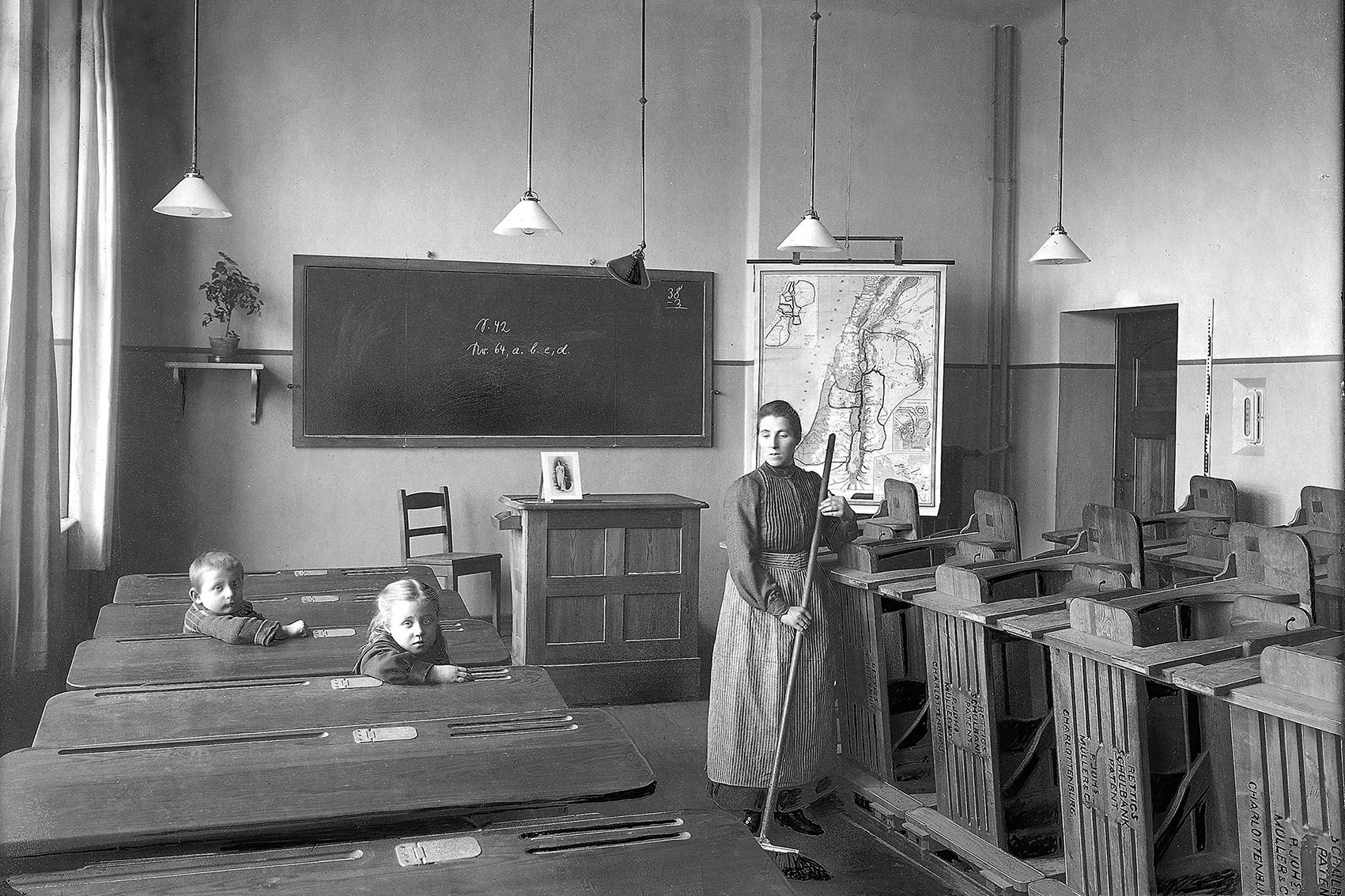 A woman sweeps next to flipped-up Rettig benches in a classroom