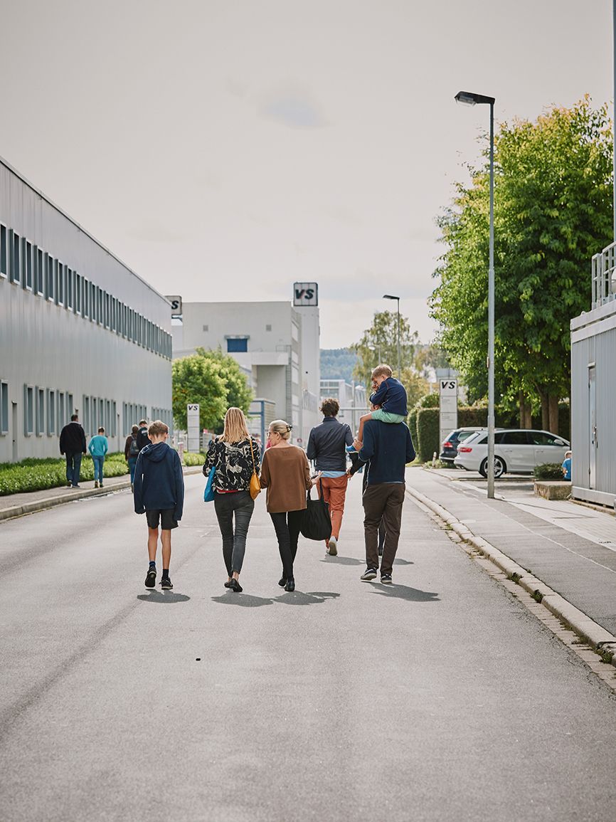 Visitors walk along Hochhäuser Strasse next to the VS factory