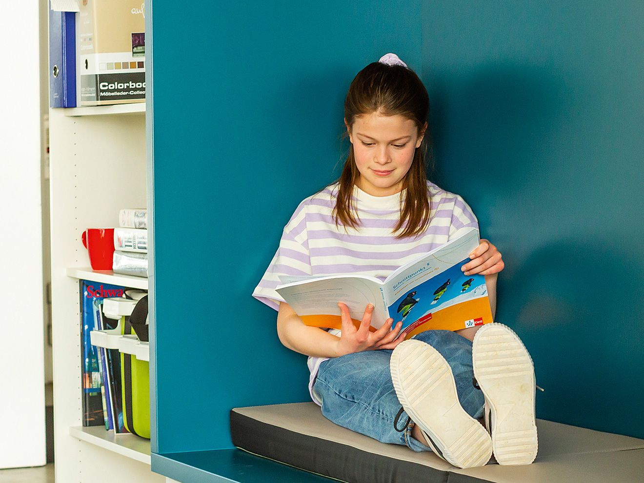 A girl sits in an alcove and reads