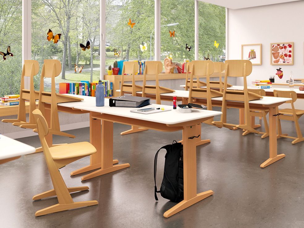 Ein Klassenzimmer mit modernen Holzkufentischen und -stühlen von VS, einige davon mit Huckepackfunktion aufgestuhlt.