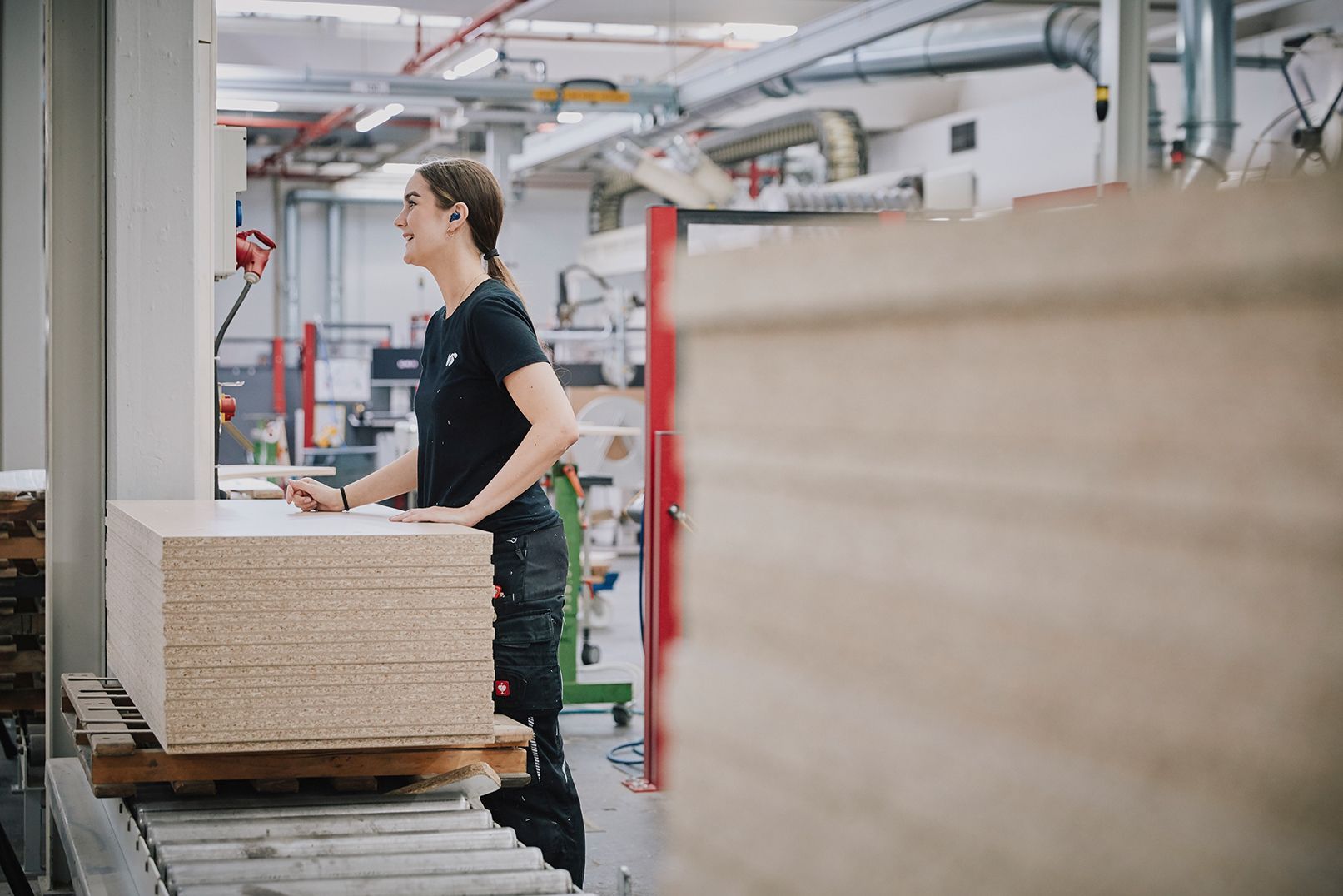 Eine Mitarbeiterin arbeitet an einem Stapel Spanplatten in der Fertigung von VS.