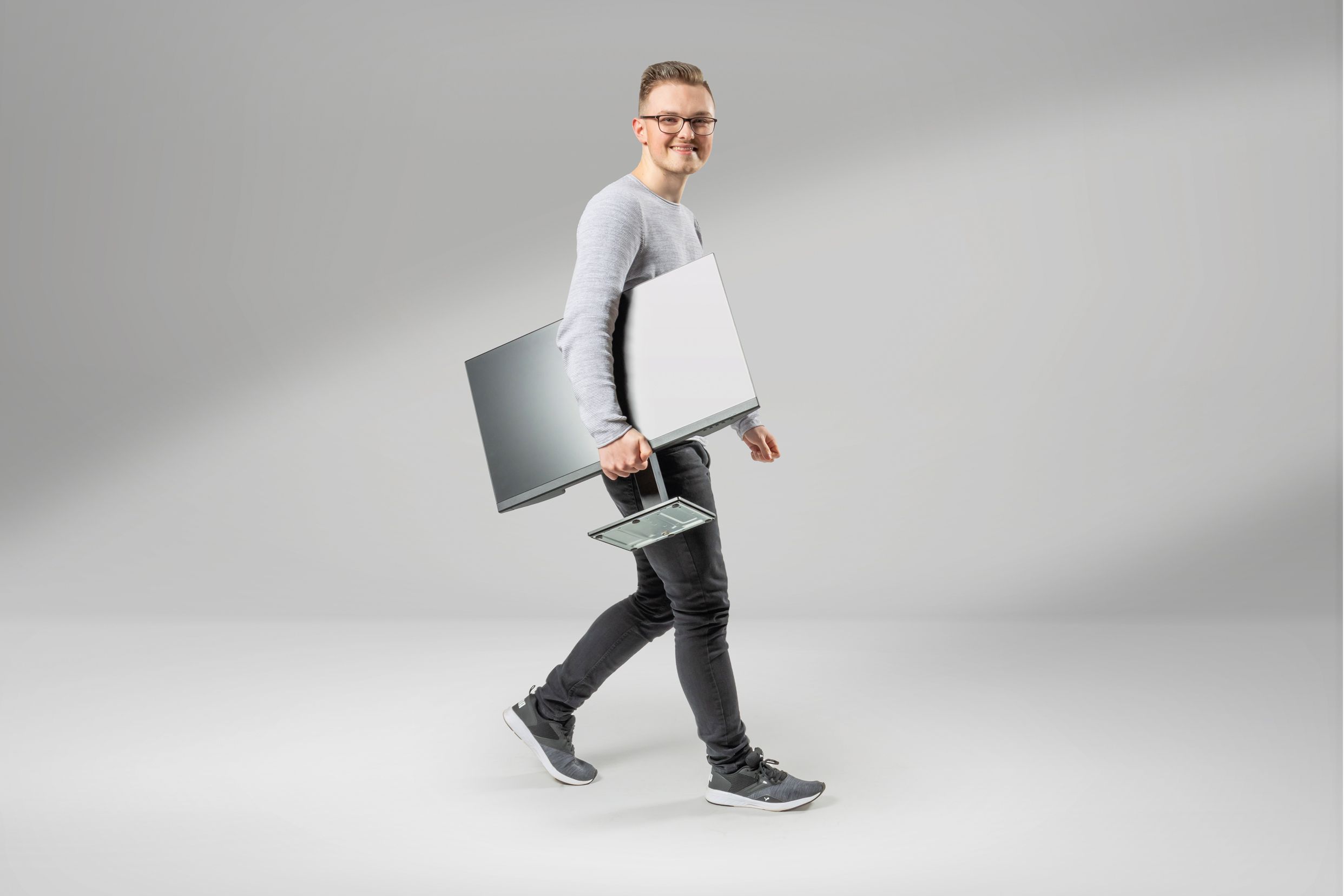 A young computer science student with a screen under his arm smiles at the camera