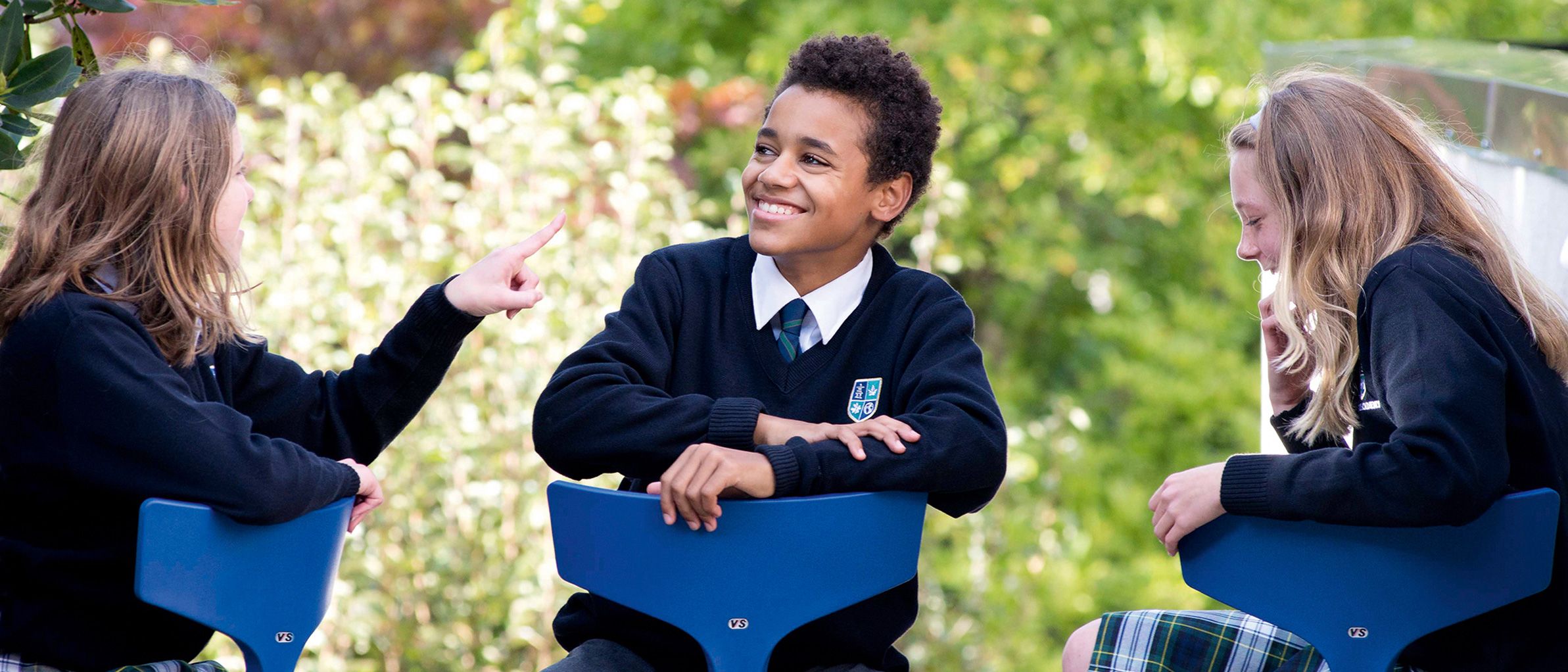 Three pupils sit on the Stakki chair in different positions, facing forwards, sideways or sitting astride.