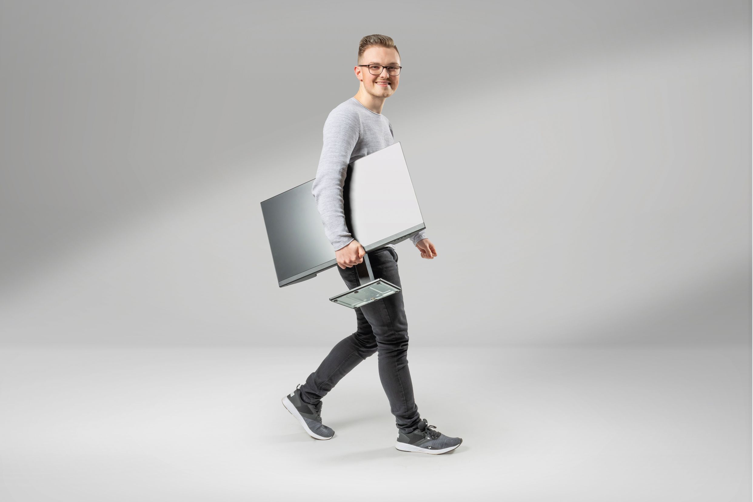 Ein junger Student der Informatik mit Bildschirm unter dem Arm lächelt in die Kamera