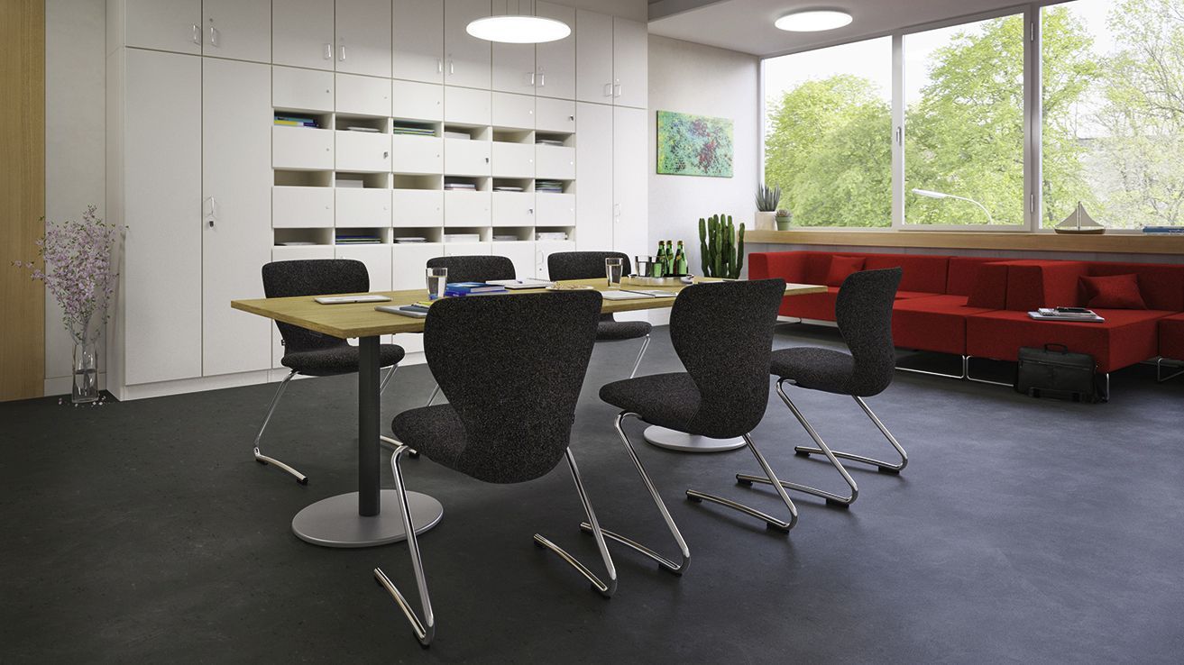 gepolsterte PantoSwing-Soft Lehrerstühle an einem VS-Bürotisch vor dem Sofa LowBack in einem Lehrerzimmer