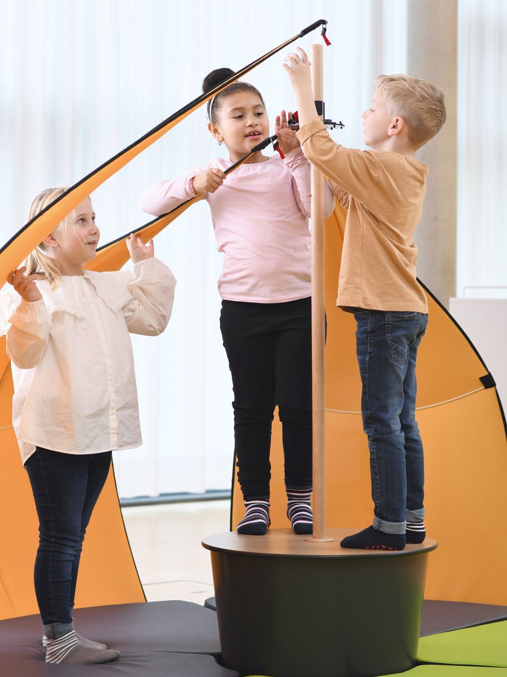 Three children set up the tent element Leaf by VS for floor-level learning.