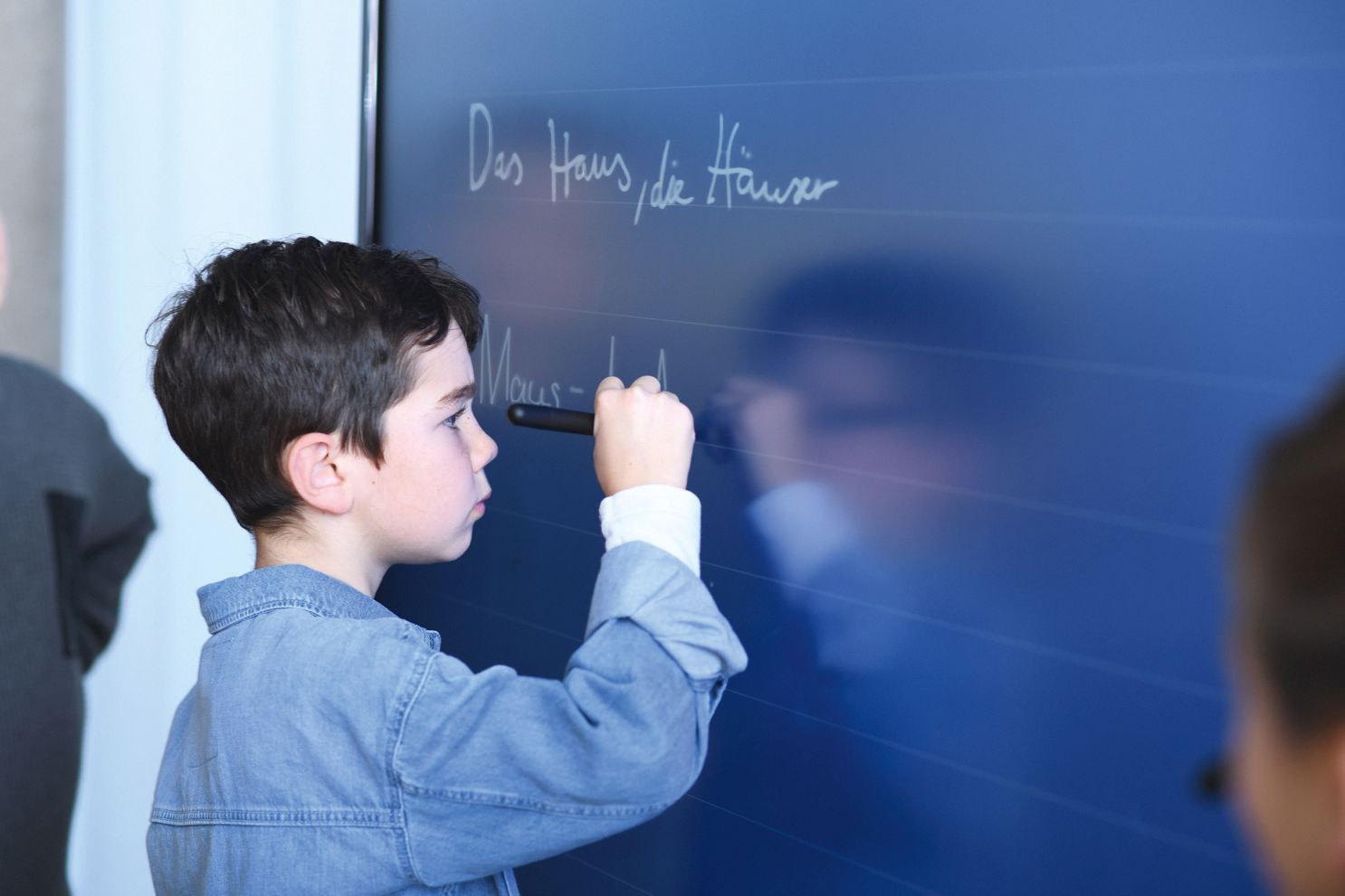 A boy writes on an interactive whiteboard.