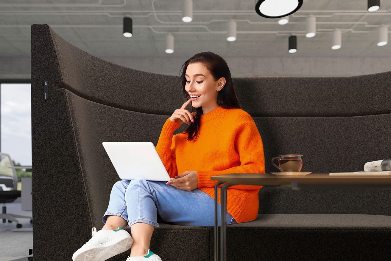 Eine Frau arbeitet an ihrem Laptop im halbrunden Sessel mit hoher Rückenlehne HiBack der Serie Lounge von VS