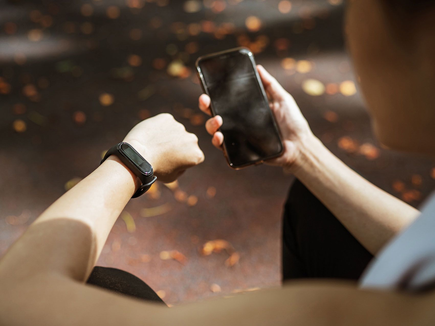 Ein Mann schaut auf seine SmartWatch und hält sein Handy in der Hand.