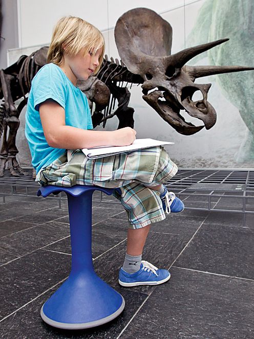 A boy draws sitting on a blue Hokki made by VS in the Senckenberg Natural History Museum in Frankfurt